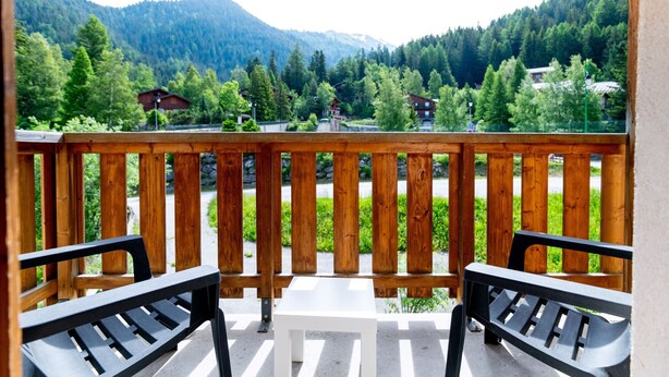 Een balkon met houten leuningen en twee zwarte bankjes.