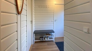 Un couloir avec un meuble à chaussures et un banc.