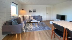 Un salon confortable avec un canapé, une petite table, un téléviseur et une table à manger.