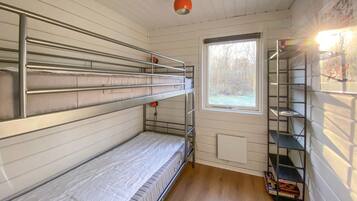 Une chambre avec un lit superposé, une fenêtre, un radiateur et une étagère avec quelques objets.