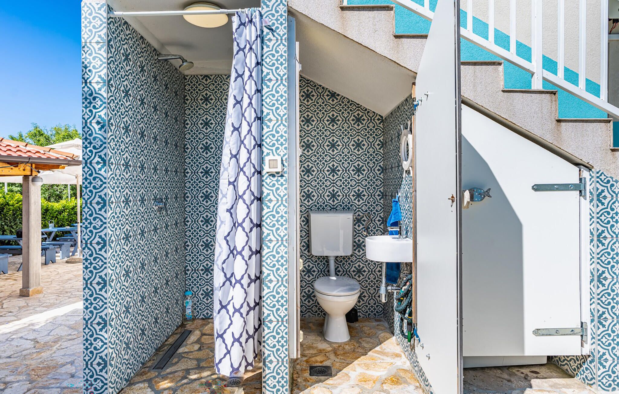 A bathroom with patterned tiles, a toilet, a sink, and a shower curtain.