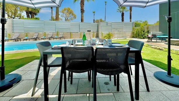 A patio with a pool, outdoor seating, and umbrellas. - New! Audrey's Luxury Retreat - Walk Downtown (Palm Springs)