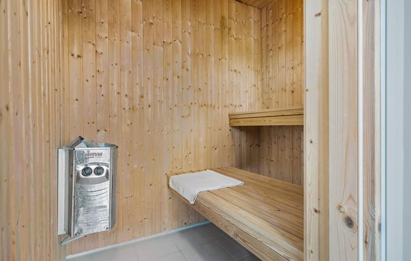 Un cuarto de sauna con paredes de madera, un banco y un calentador.