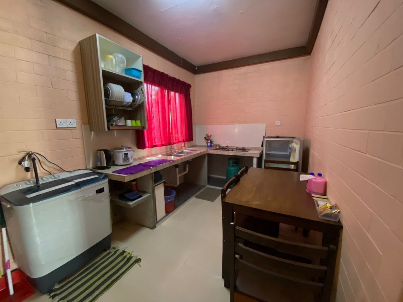Eine kompakte Küche mit Toaster, Spüle, kleinem Kühlschrank und einem Holztisch.