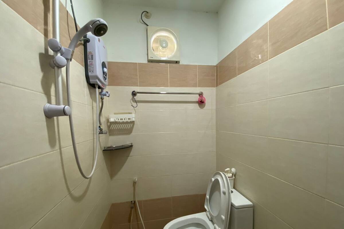 Ein kleines Badezimmer mit Fliesen, einer Toilette, einem Händetrockner und einem Wandheizkörper.