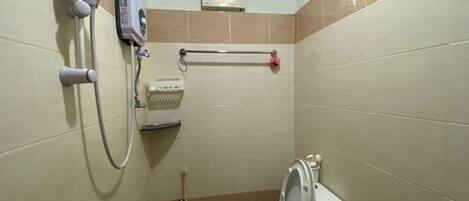 A small, tiled bathroom with a toilet, a hand dryer, and a wall-mounted heater.