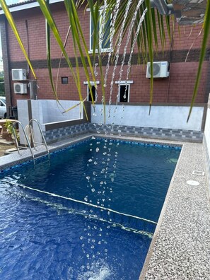 A swimming pool with clear water, surrounded by a tiled deck and a brick wall. - Chalet TM3 Langkawi (Langkawi)