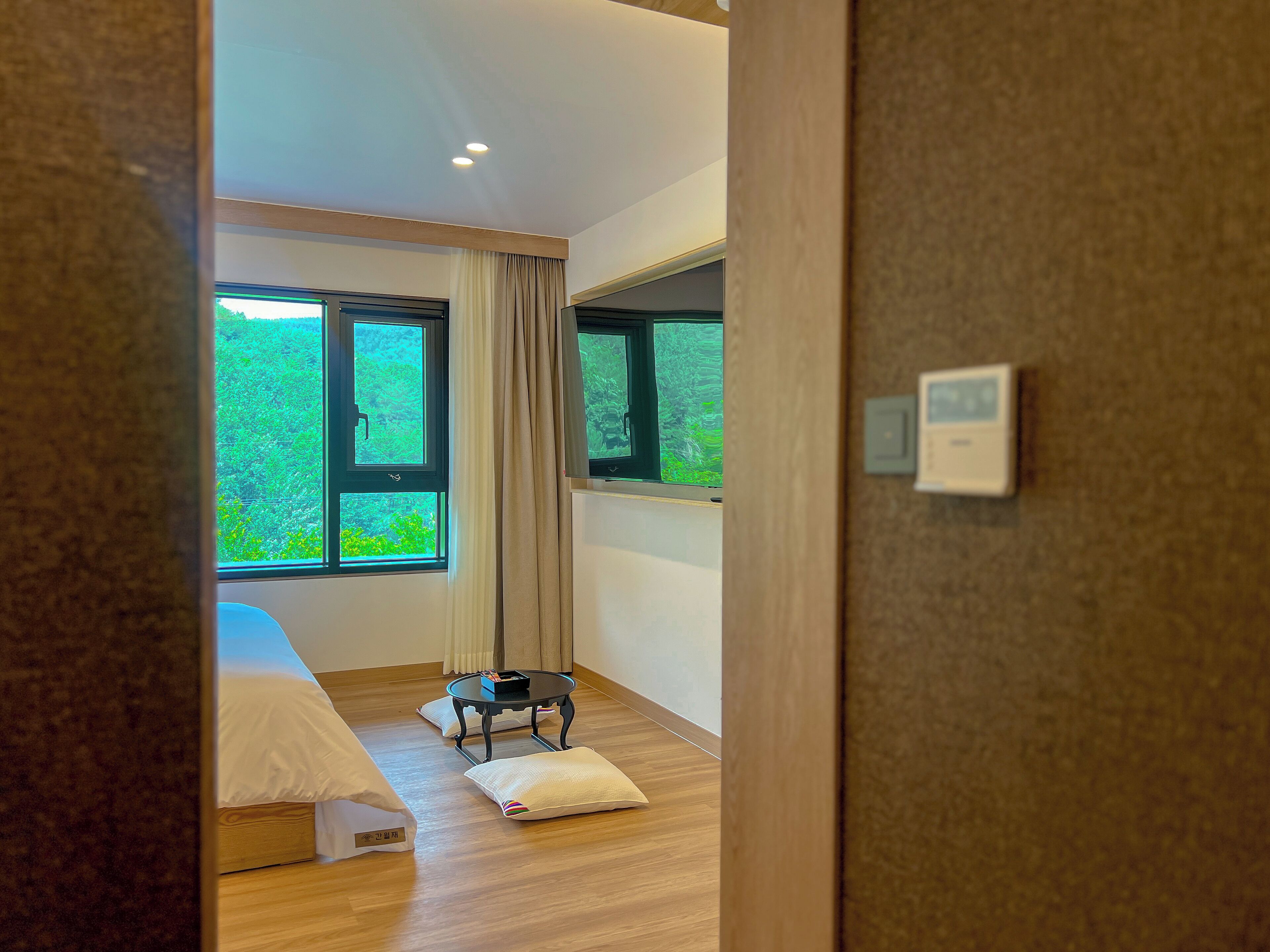 A bedroom with a bed, a bedside table, a window, and a door.