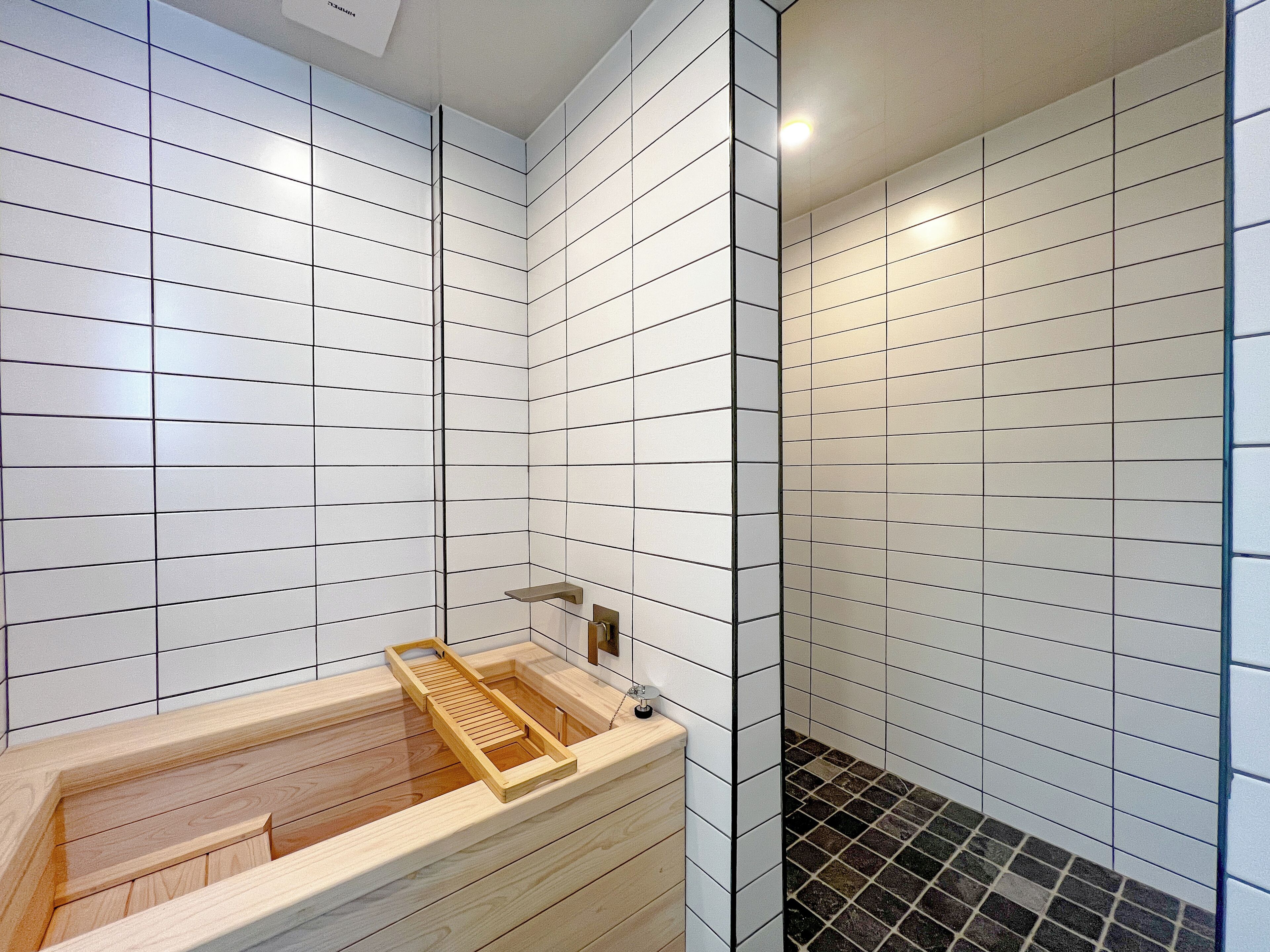 Un baño moderno con paredes de azulejos blancos y una bañera de madera.