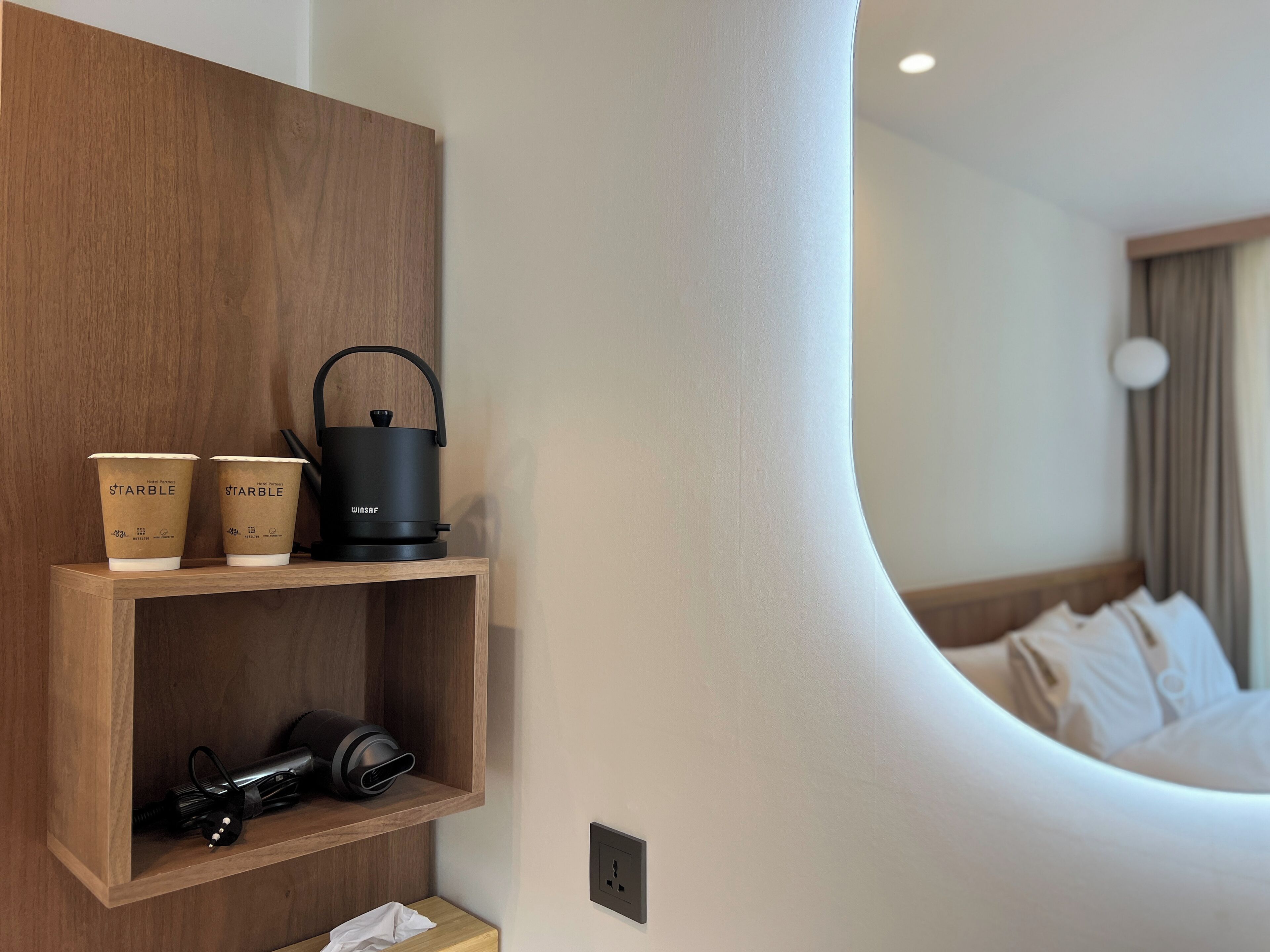 A hotel room with a wooden shelf holding a coffee maker and two cups labeled "STARBLE".