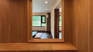 A wooden-framed doorway leading to a room with a bed, a window, and a view of greenery outside. - HOTEL KANWOLGE (Ulsan)