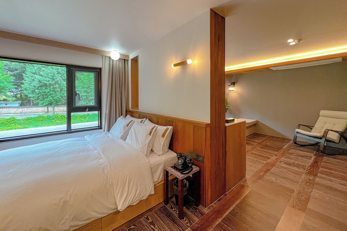 Ein modernes Hotelzimmer mit einem großen Bett, einem Schreibtisch mit Telefon und einem Sessel.
