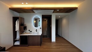 A modern hotel room with a wooden floor, a large bed, a bathroom with a round mirror, and a wooden ceiling. - HOTEL KANWOLGE (Ulsan)