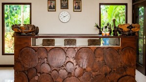 Un comptoir d’accueil avec une horloge, des photos encadrées et une vue sur la verdure à l’extérieur.