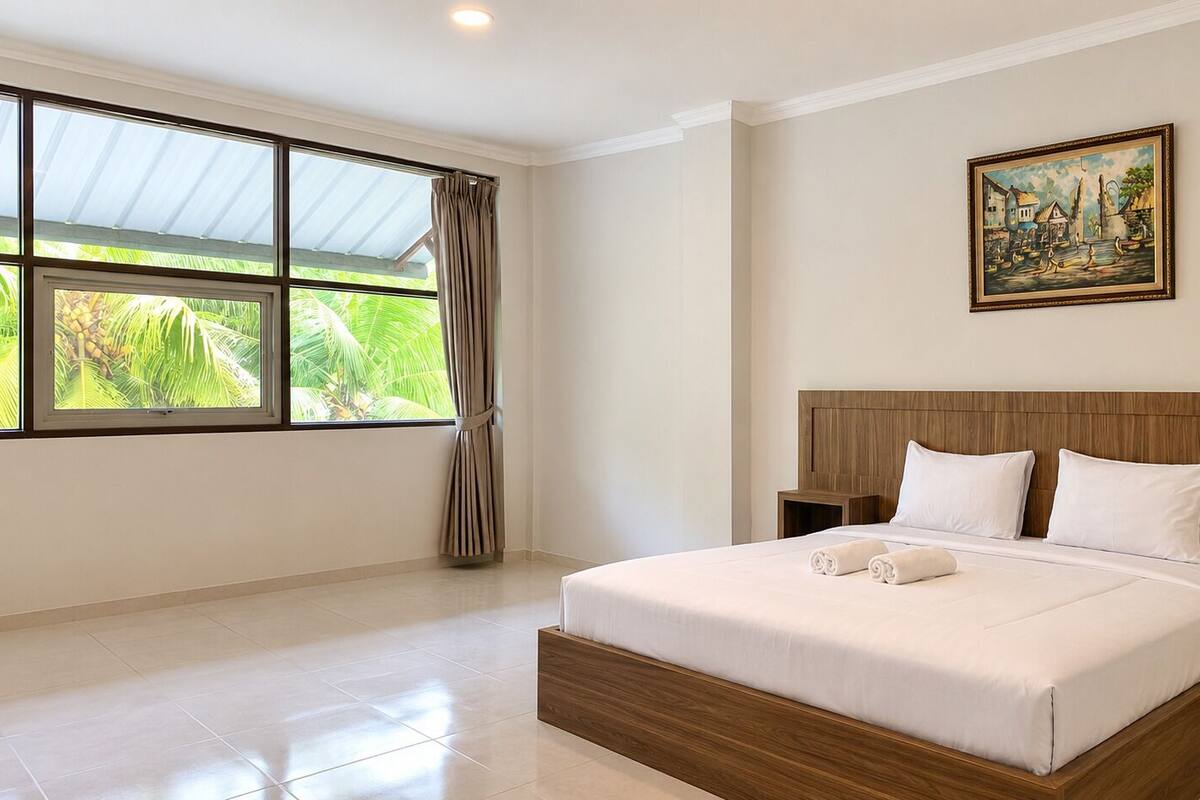A bedroom with a large bed, a nightstand, a painting on the wall, and a window with curtains.