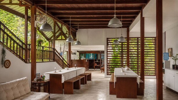 Une cuisine spacieuse avec des poutres en bois, des luminaires suspendus et un îlot central.