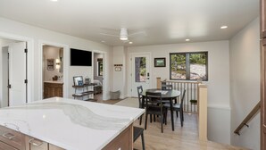 A spacious kitchen with a marble countertop, wooden cabinets, and a dining area with a table and chairs. - Cozy Guest House In The Chugach Mountains  (Anchorage)