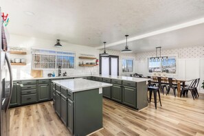 A modern kitchen with dark cabinets, a large island, and a dining area with a table and chairs.