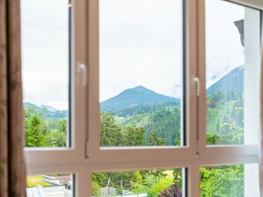 A window with a view of a mountainous landscape, including trees and a hill.
