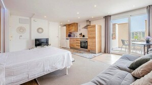 Une chambre moderne dotée d’un grand lit, d’une télévision et d’un balcon avec un espace salon extérieur.