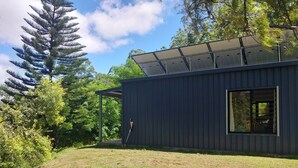 A modern building with a solar panel roof, surrounded by greenery and trees. - Private cottage on 40 acres with private creek and spectacular views.  (Eden Creek)