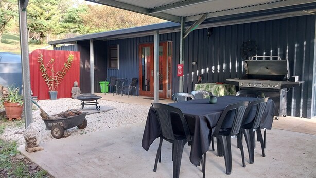 An outdoor patio with a table and chairs, a barbecue grill, and a Buddha statue. - Private cottage on 40 acres with private creek and spectacular views.  (Eden Creek)
