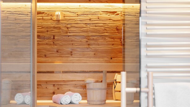 Eine Sauna mit Holzbänken, Handtüchern und einem Holzeimer.