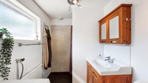 A bathroom with a white sink, wooden cabinets, a mirror, and a shower area. - Awesome home in Vittsjö with WiFi (Vittsjö)