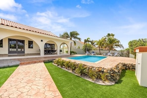 Ein modernes Haus mit Schwimmbad, Terrasse und Garten.