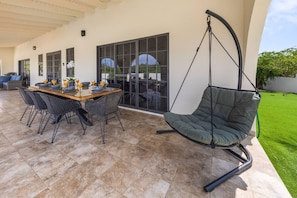 An outdoor patio with a dining table, chairs, and a hanging chair.