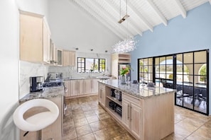 A spacious kitchen with a large island, marble countertops, and a view of an outdoor patio.