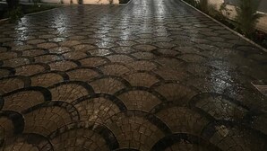 A nighttime outdoor area with a wet cobblestone pathway leading to a building.