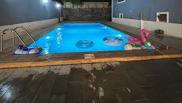 A swimming pool with a wooden deck, a ladder, and a flamingo float.