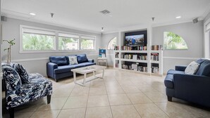 Ein geräumiges Wohnzimmer mit einem blauen Sofa, einem Couchtisch und einem Bücherregal voller Bücher.