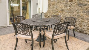 A round outdoor table with six chairs, a white umbrella, and a stone wall in the background. - THE FARM COTTAGE, family friendly in Athy, County Kildare (Athy)