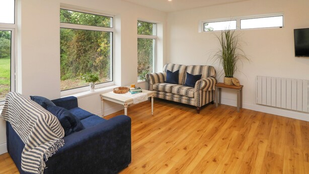 A modern living room with a sofa, armchair, and a small table with a plant. - THE FARM COTTAGE, family friendly in Athy, County Kildare (Athy)