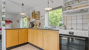 A kitchen with wooden cabinets, a stove, and a window with a view of greenery. - 2 bedroom amazing home in Stege (Stege)
