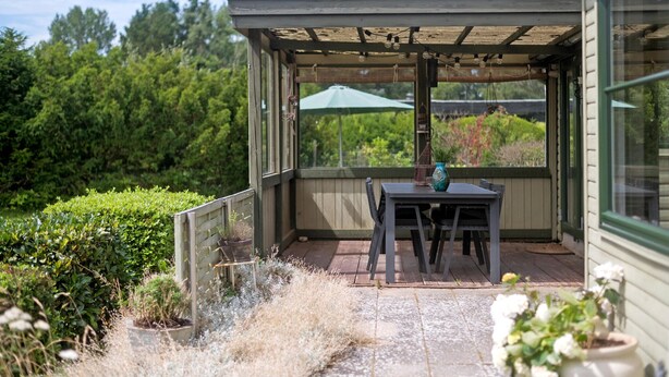 A covered patio with a table and chairs, surrounded by potted plants and a view of a garden. - 2 bedroom amazing home in Stege (Stege)