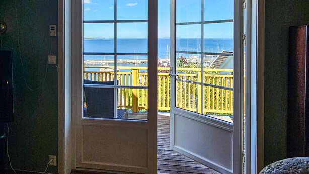 A room with a large window revealing a wooden deck and a view of the sea. - Nice home in åsgårdstrand (Åsgårdstrand)