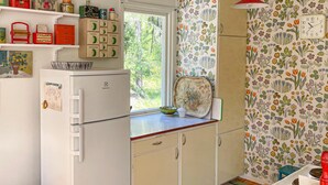 A compact kitchen with a refrigerator, a window, and a floral-patterned wall. - Awesome home in Gräddö with WiFi (Gräddö)