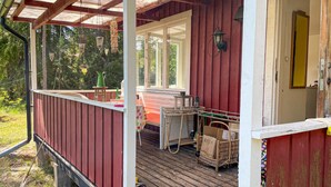 A wooden deck with a red railing, a table with chairs, and a basket of items. - Awesome home in Gräddö with WiFi (Gräddö)