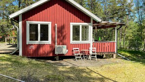 A red cabin with two windows, a small porch, and outdoor seating. - Awesome home in Gräddö with WiFi (Gräddö)