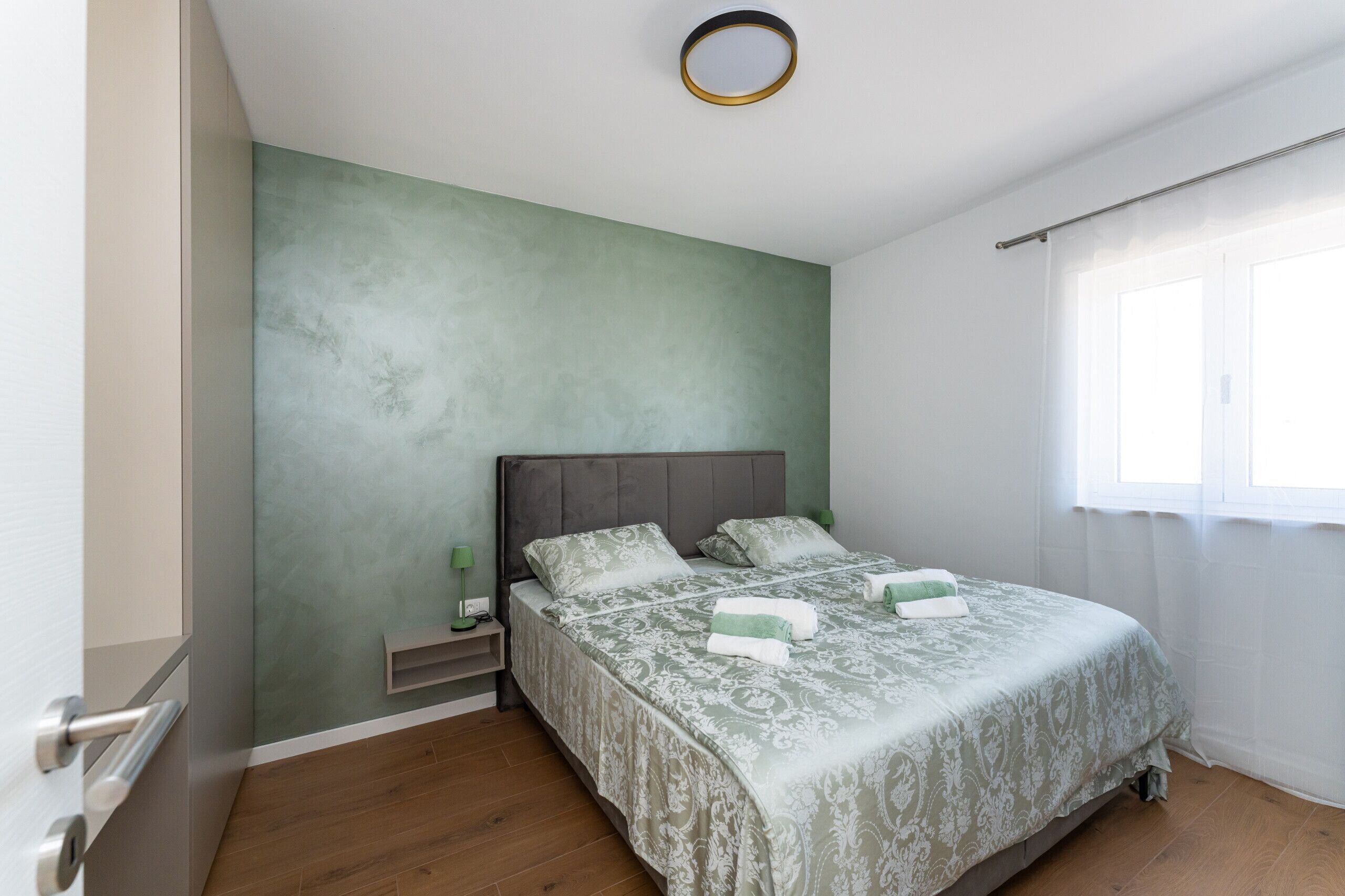 A bedroom with a bed, bedside tables, and a window with curtains.