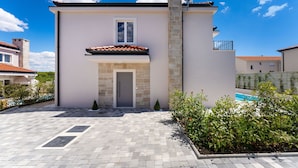A modern two-story house with a tiled roof, a stone chimney, and a small balcony. - Villa Casa Coral with pool (Crno)