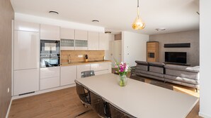 A modern kitchen with white cabinets, a central island, and a dining area. - Villa Casa Coral with pool (Crno)
