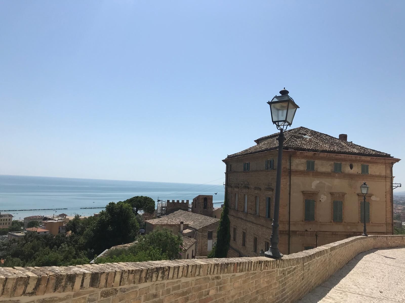 Un edificio storico con tetto in tegole, un lampione e vista sul mare.