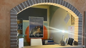 A reception desk with a framed poster, a glass bottle, and a small table. - B&B Miramare Grottammare (Grottammare)