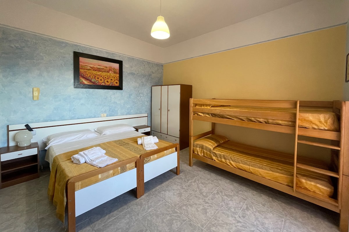 A bedroom with two beds, a wardrobe, a painting, and a ceiling light.