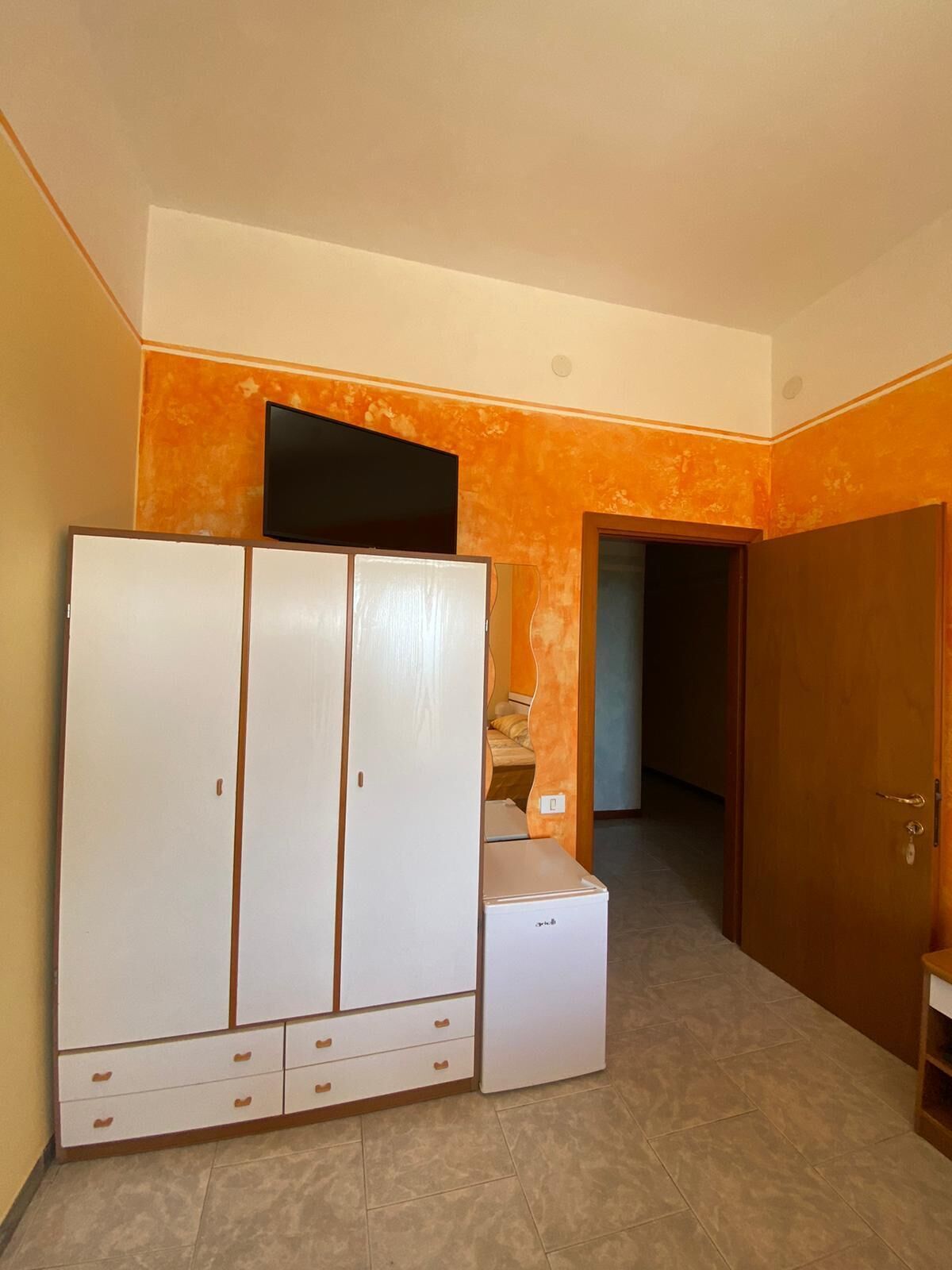 Una stanza con un armadio, una televisione e un letto.