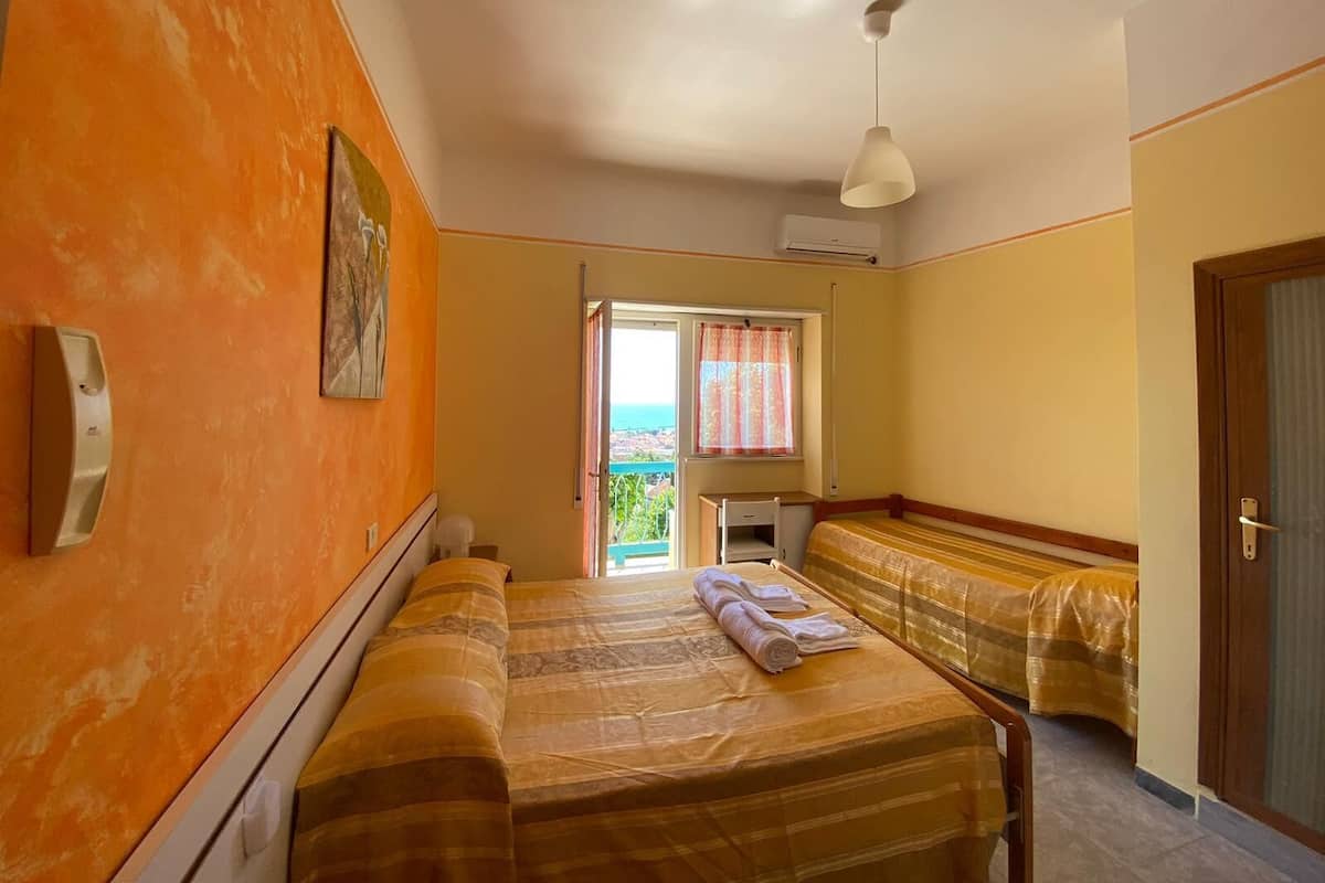 A room with a bed, a desk, and a window with curtains.